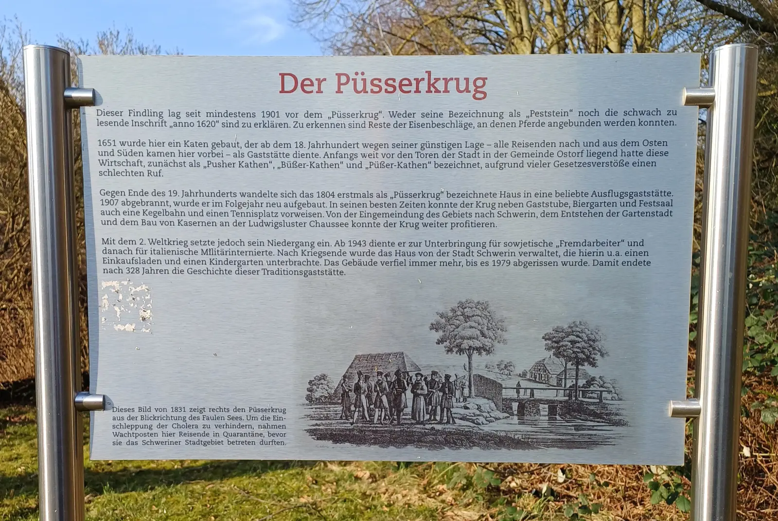 Großer Findling im Gras, daneben eine Informationstafel zum Püsserkrug