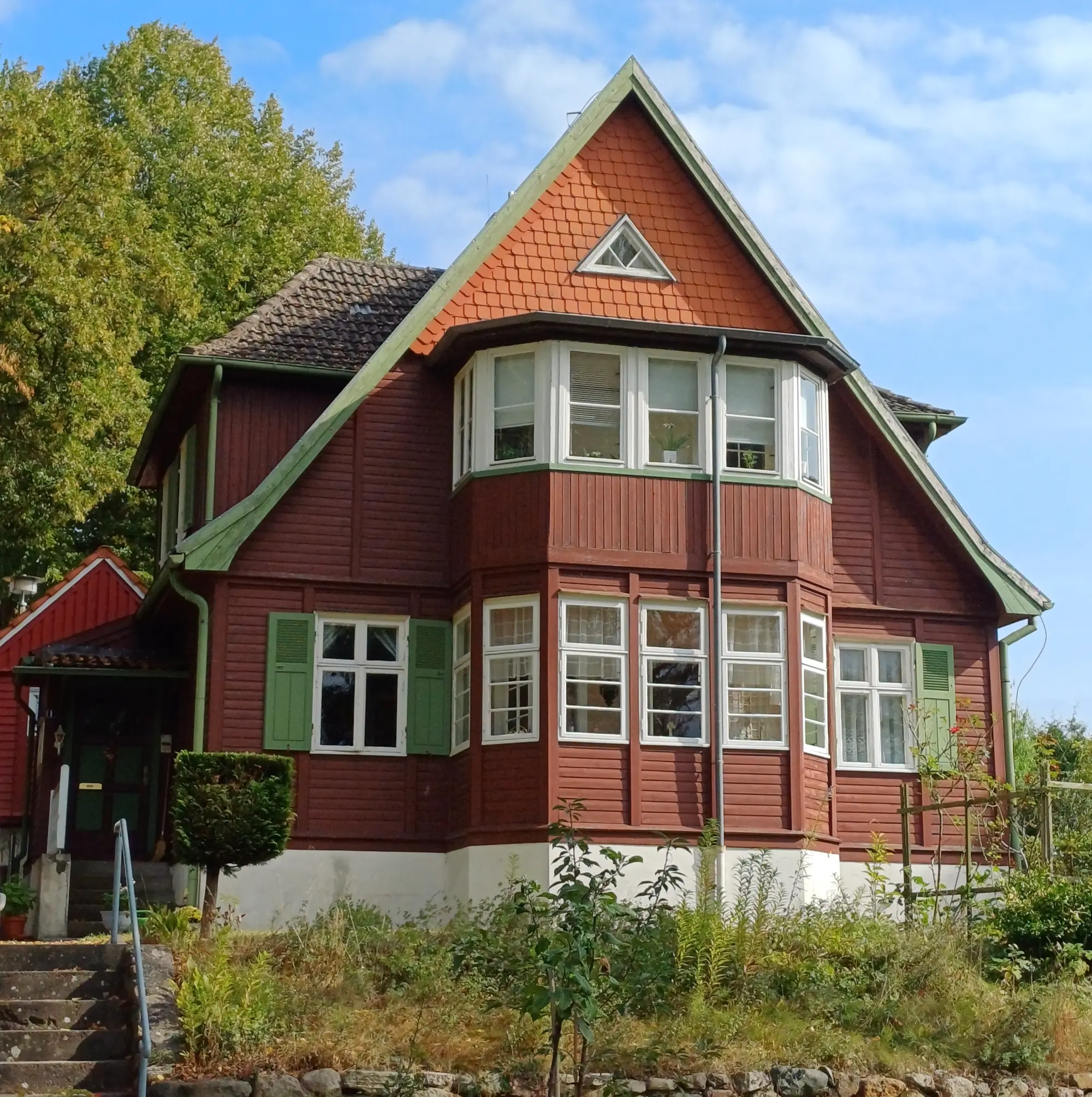 Rotbraunes Holzhaus mit Erker und Spitzgiebel in der Haselholzstraße 1