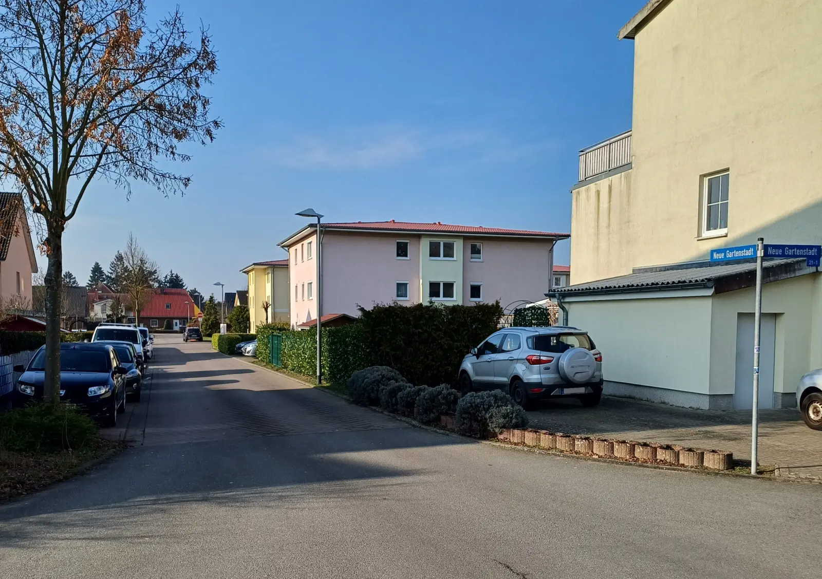 Wohnstraße mit Mehrfamilienhäusern und Hecken in der Neuen Gartenstadt
